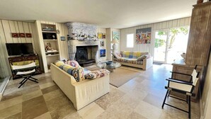 Una sala de estar con chimenea, sofá, sillón y mueble para televisión.