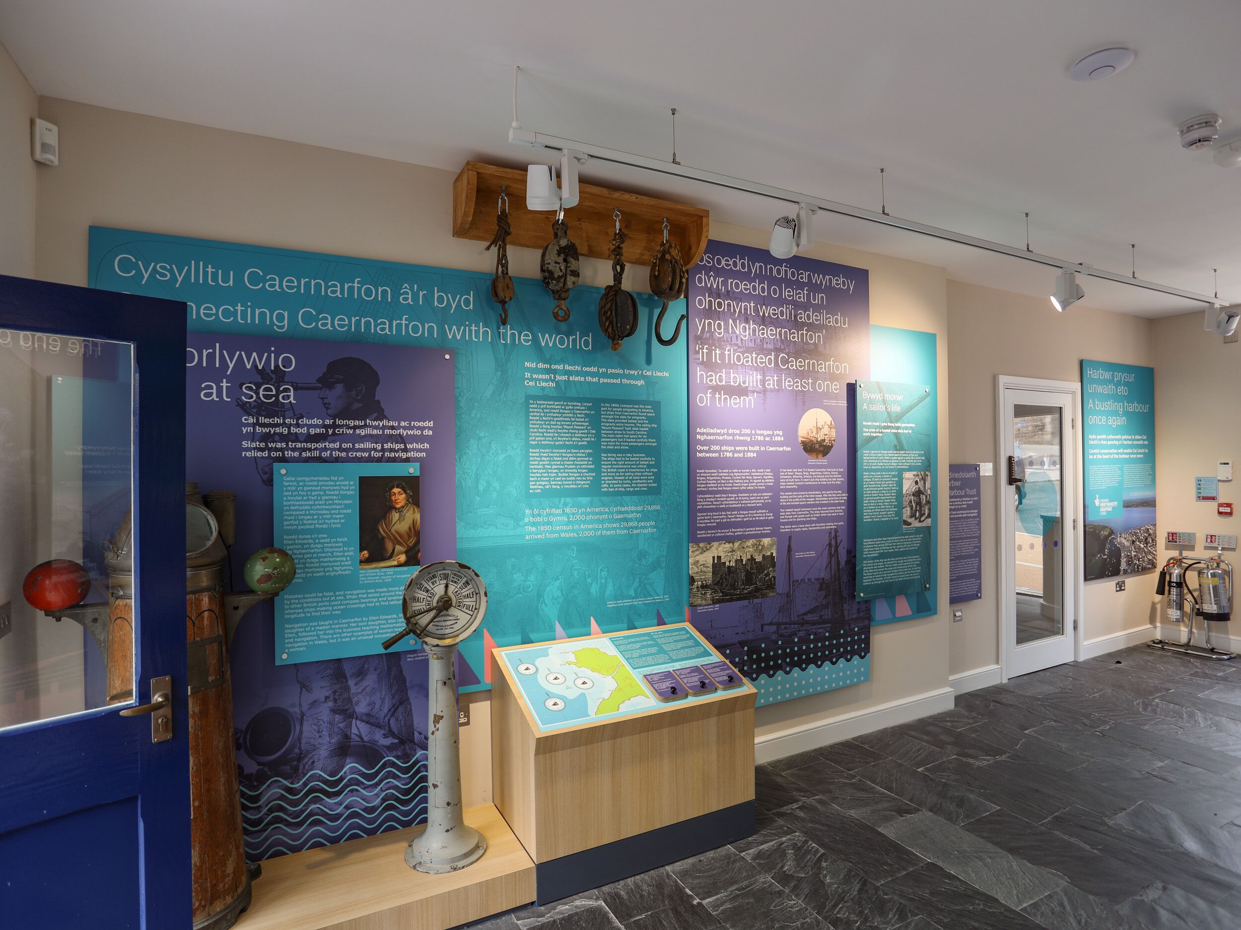 A maritime exhibit with informational panels, a ship's wheel, and a wooden display case.