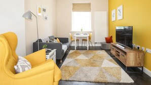 A modern living room with a sofa, a dining table, and a TV. - Moel Tryfan (Caernarfon)