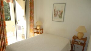 Une chambre avec un grand lit, deux tables de chevet avec des lampes, une fenêtre avec des rideaux et un tableau au mur.