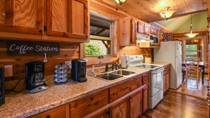 A kitchen with wooden cabinets, a coffee station, stainless steel appliances, and a view of the outdoors.