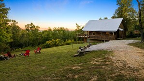 A rustic lodge with a metal roof, surrounded by a grassy area with red Adirondack chairs.