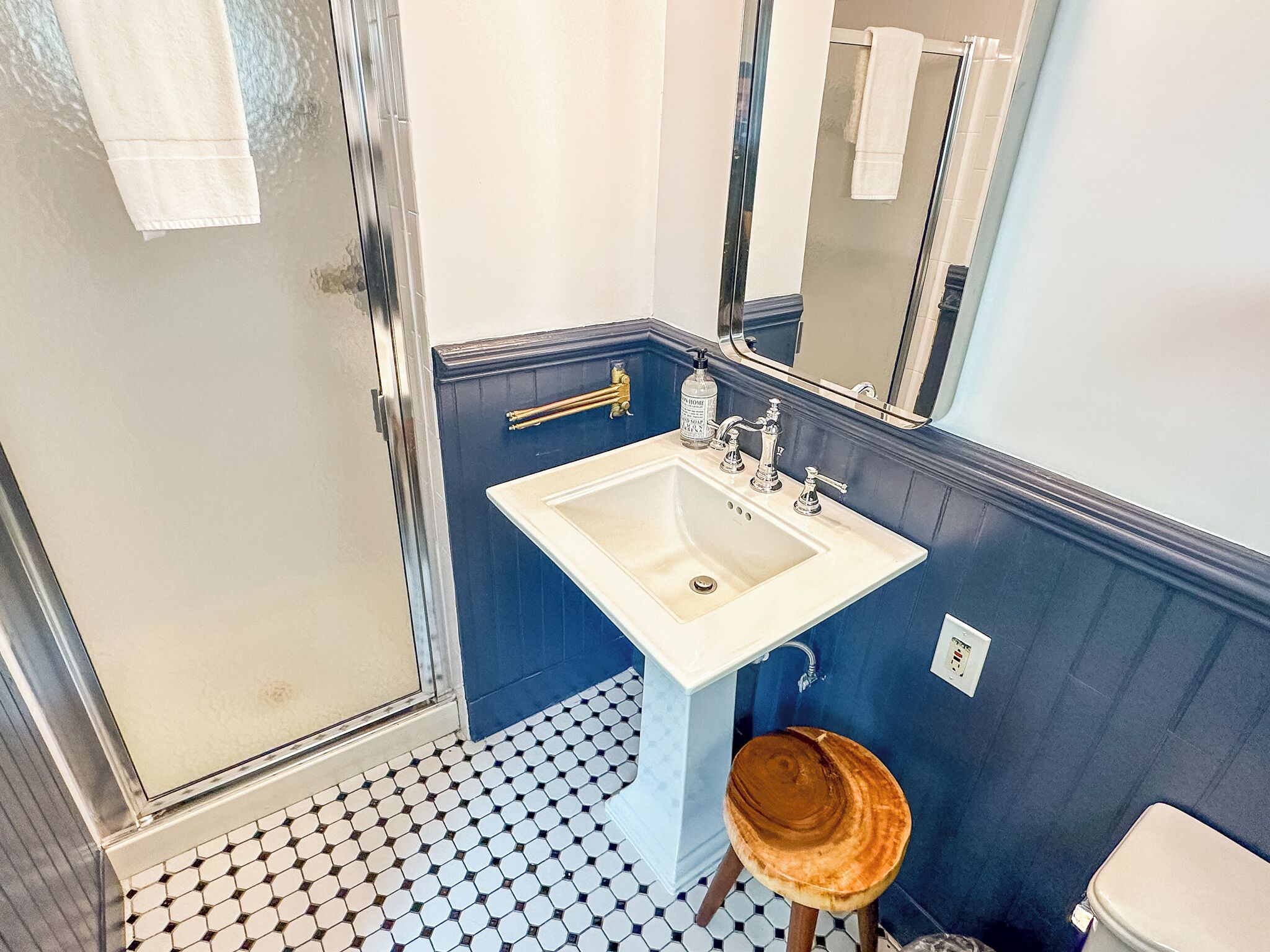A bathroom with a white sink, blue walls, a mirror, and a shower.