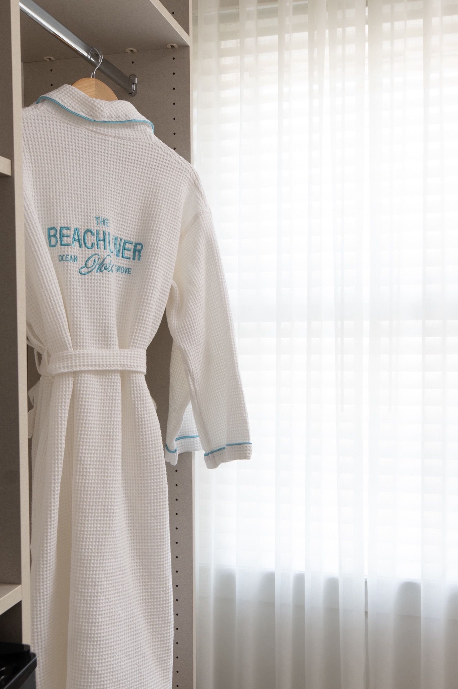 Un peignoir blanc avec une inscription, suspendu à un portant métallique.