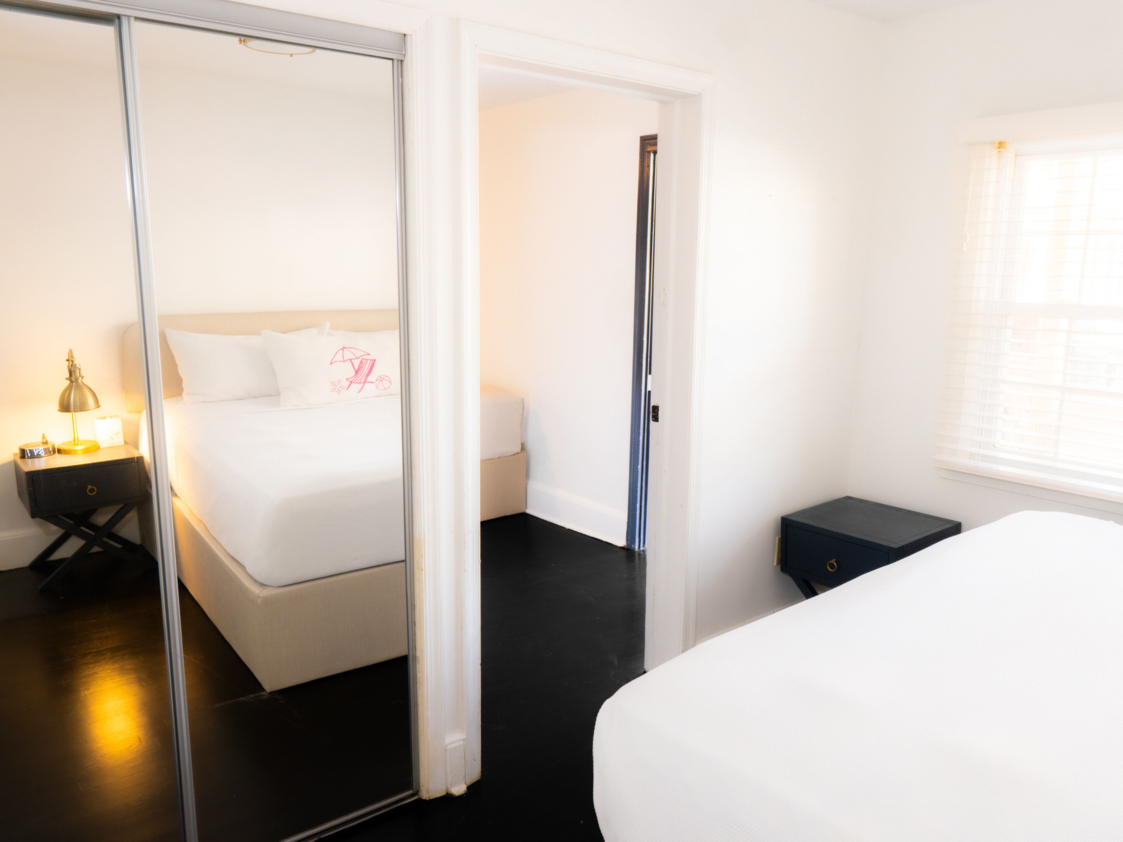A hotel room with a bed, a nightstand, a mirror, and a window.