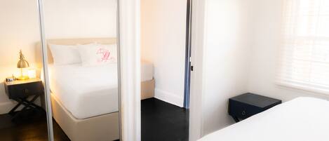 A hotel room with a bed, a nightstand, a mirror, and a window.