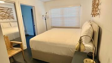 Une chambre à coucher avec un lit, une lampe de chevet et une fenêtre avec des stores.