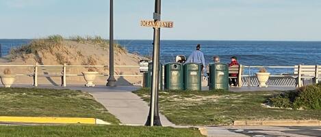Un paseo marítimo bordeado de bancos, con una señal de calle que dice 'Ocean Avenue' y vistas al océano.