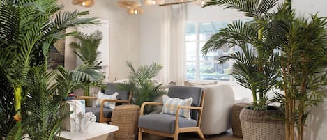 A modern living room with a sofa, armchairs, and potted plants.