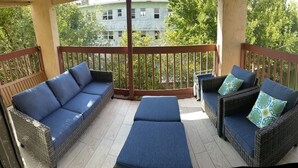 A balcony with wicker furniture and cushions, a wooden railing, and a view of buildings and trees. - BEAUTIFUL & SPACIOUS 2BR/2BA BEACH CONDO (Jacksonville Beach)
