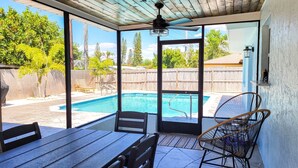 Ein überdachter Patio mit Pool, Tisch und Stühlen.