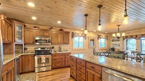 A spacious kitchen with wooden cabinets, stainless steel appliances, and a large island. - Sunset Mountain Views- Spacious Luxurious cabin (Morganton)