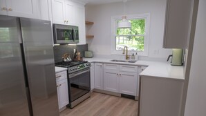 A modern kitchen with white cabinets, stainless steel appliances, and a window providing natural light. - Detox & Hike: Waterfront Oasis with Infrared Sauna & Shawangunk Mountains (wallkill)