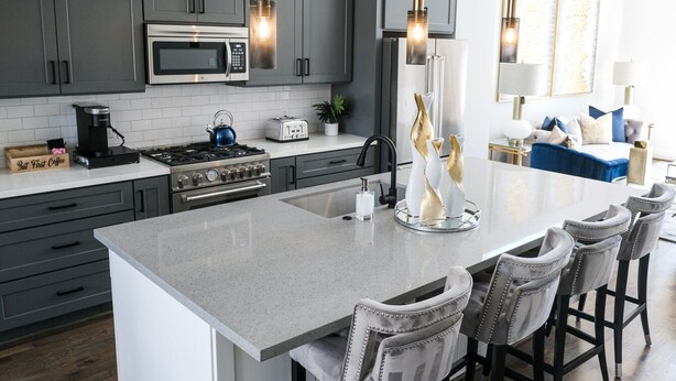 A modern kitchen with grey cabinets, stainless steel appliances, and a central island with bar stools. - Elegant Lux Townhome. 3BD, 3.5BTH. DOWNTOWN HTX (Houston)