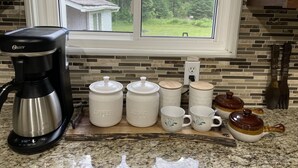 Eine Küche mit einer Kaffeemaschine, Tassen und einem Teekessel auf der Arbeitsfläche.