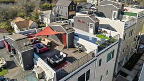 A multi-story building with a rooftop patio area featuring outdoor furniture and a barbecue grill. - Roof Top Deck with Skyline View - NO BUNKS - Pet and Kid Friendly (Nashville)