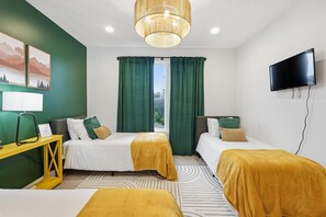 Une chambre d’hôtel avec deux lits, une télévision, un bureau et une fenêtre avec des rideaux.