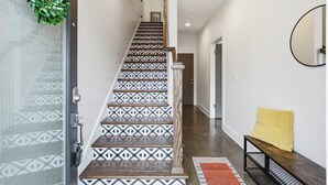 A staircase with patterned tiles, a bench with a cushion, and a mirror on the wall. - Roof Top Deck with Skyline View - NO BUNKS - Pet and Kid Friendly (Nashville)