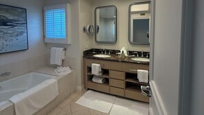 Uma casa de banho moderna com banheira, toucador com duas lavatórios e um espelho grande.