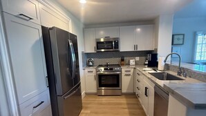 Uma cozinha moderna com armários brancos, eletrodomésticos de aço inoxidável e backsplash com padrão losango.