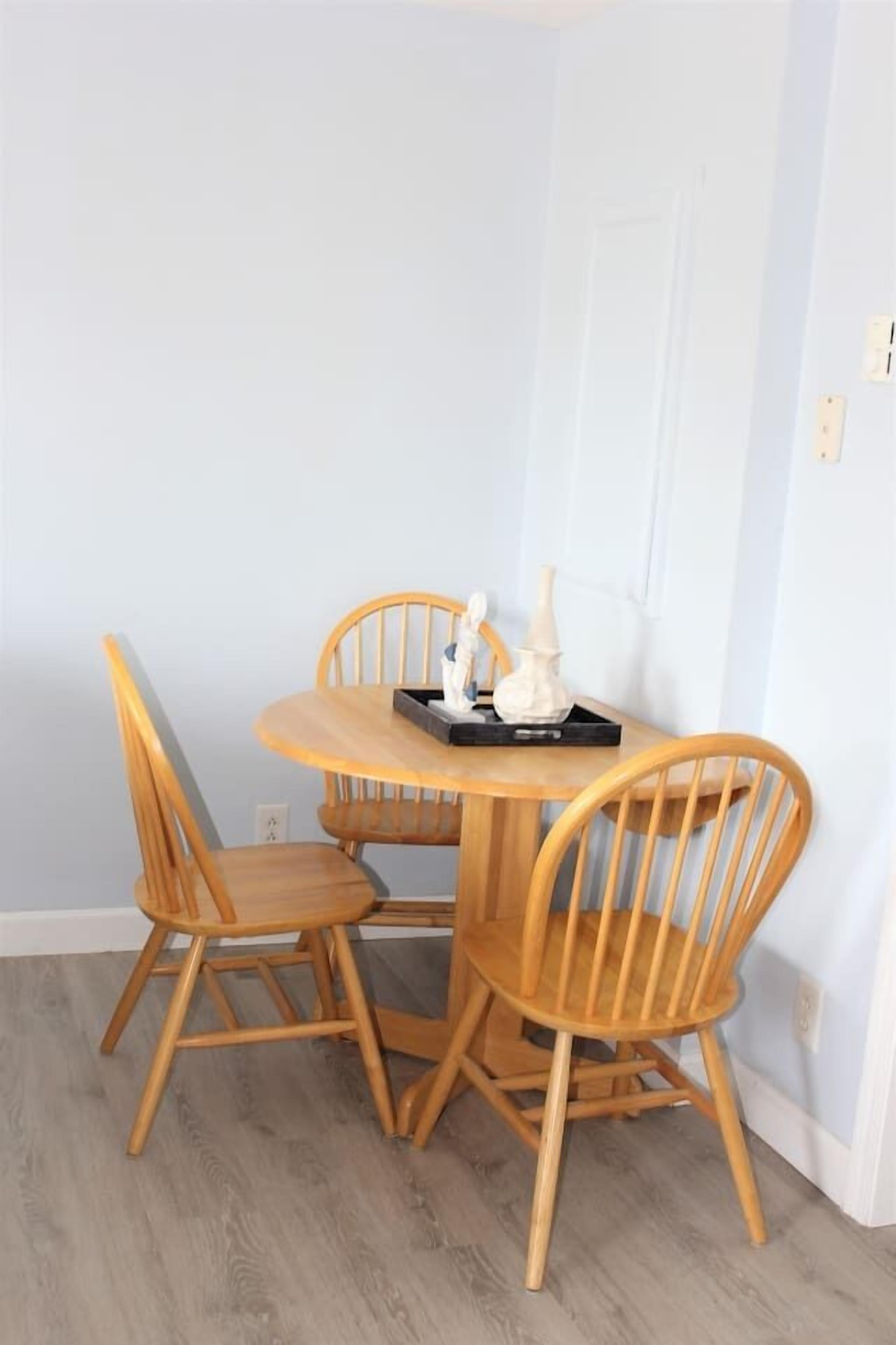 A dining area with a round wooden table and four wooden chairs.