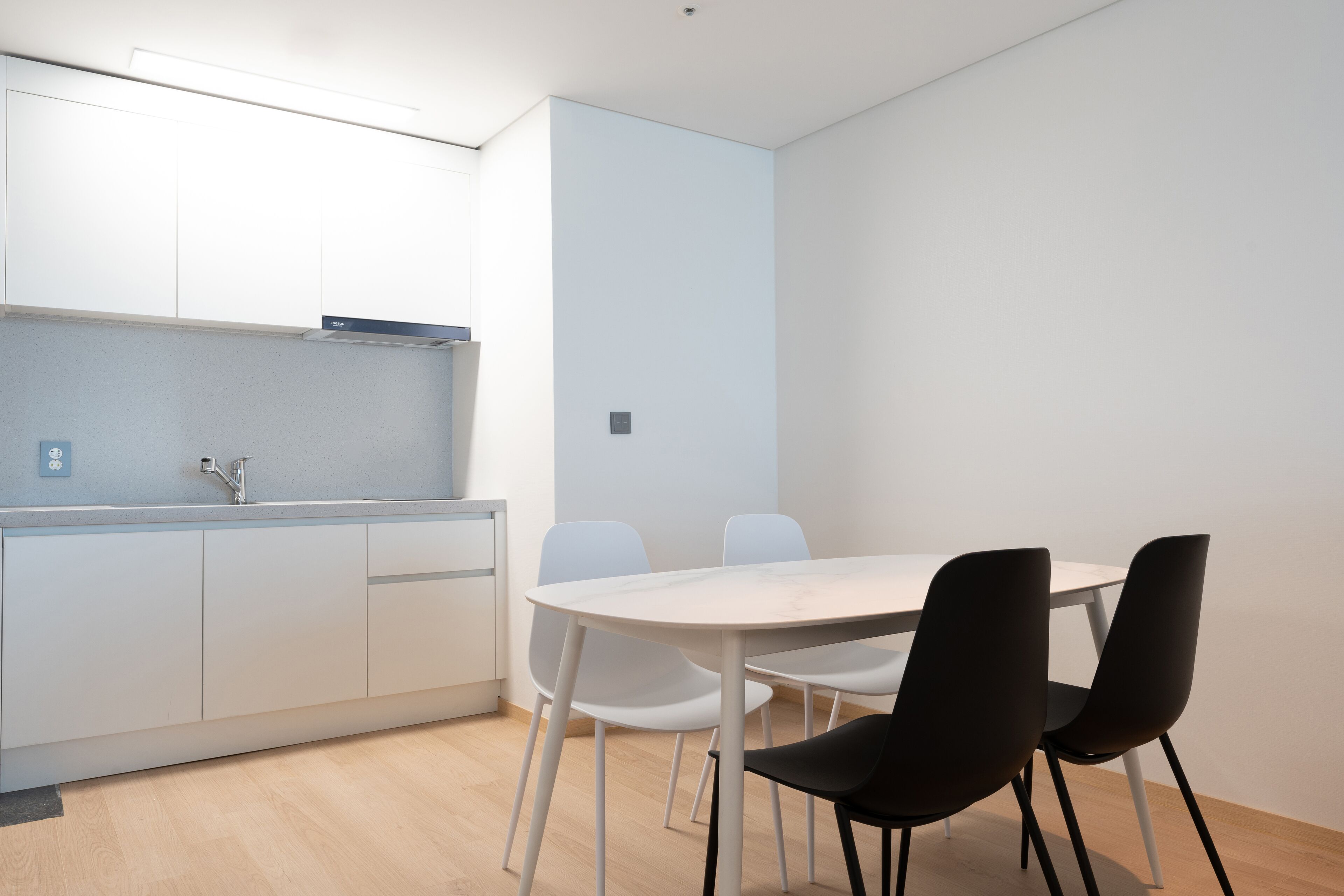 A modern kitchen with white cabinets, a white countertop, and a round table with four chairs.