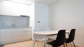 A modern kitchen with white cabinets, a white countertop, and a round table with four chairs.