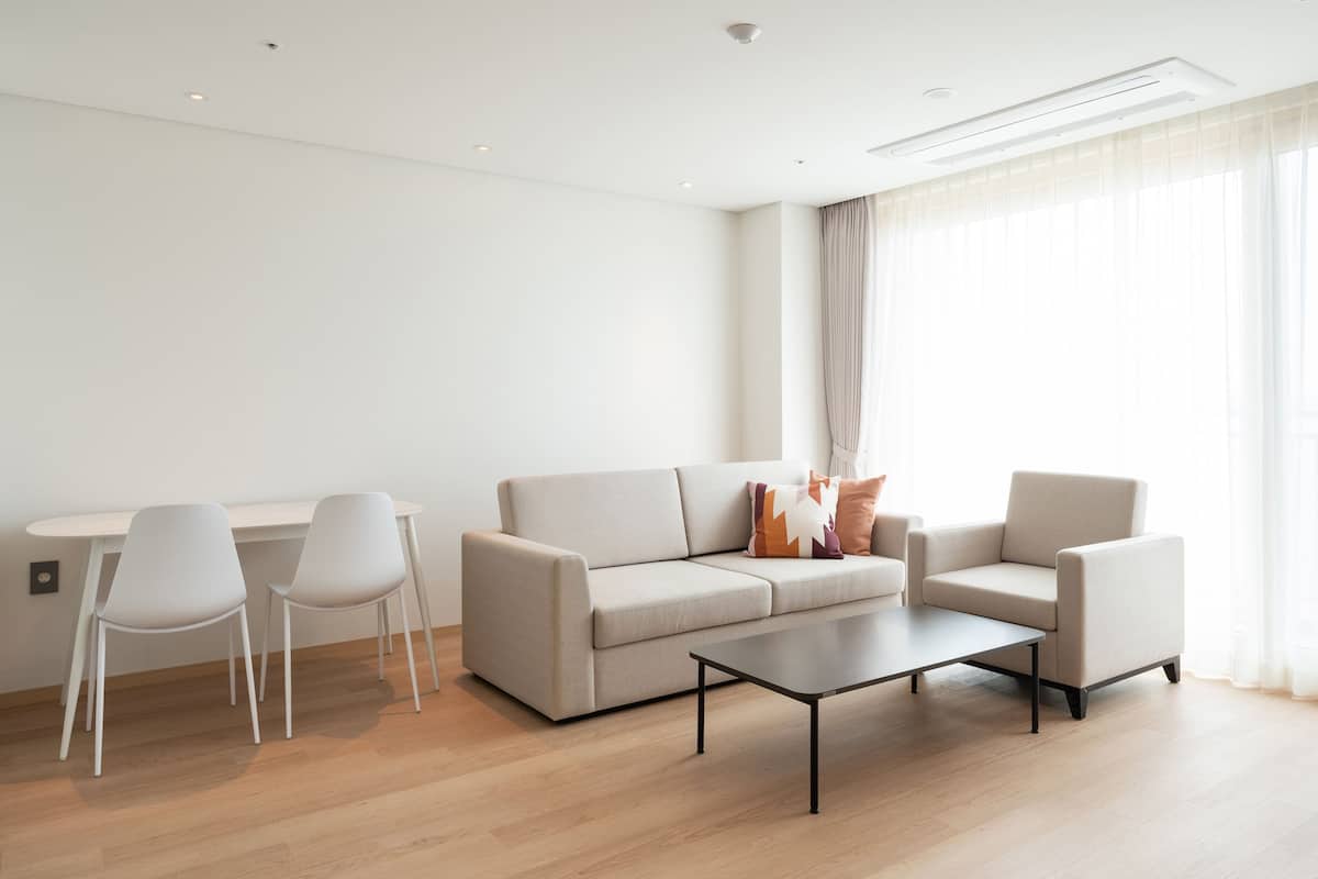 A modern living room with a sofa, two armchairs, a coffee table, and a dining table with chairs.