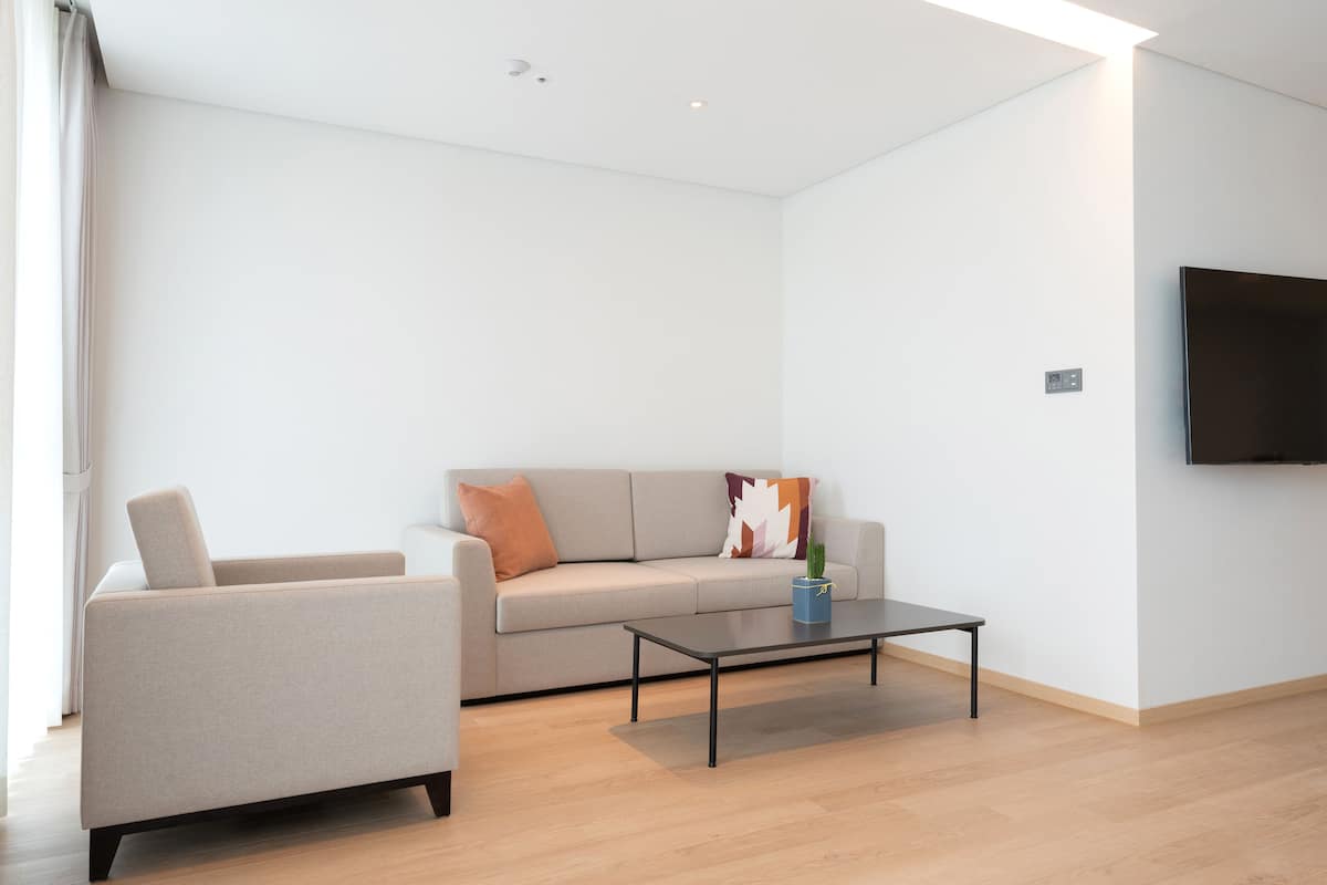 A modern living room with a sofa, a coffee table, and a flat-screen TV mounted on the wall.
