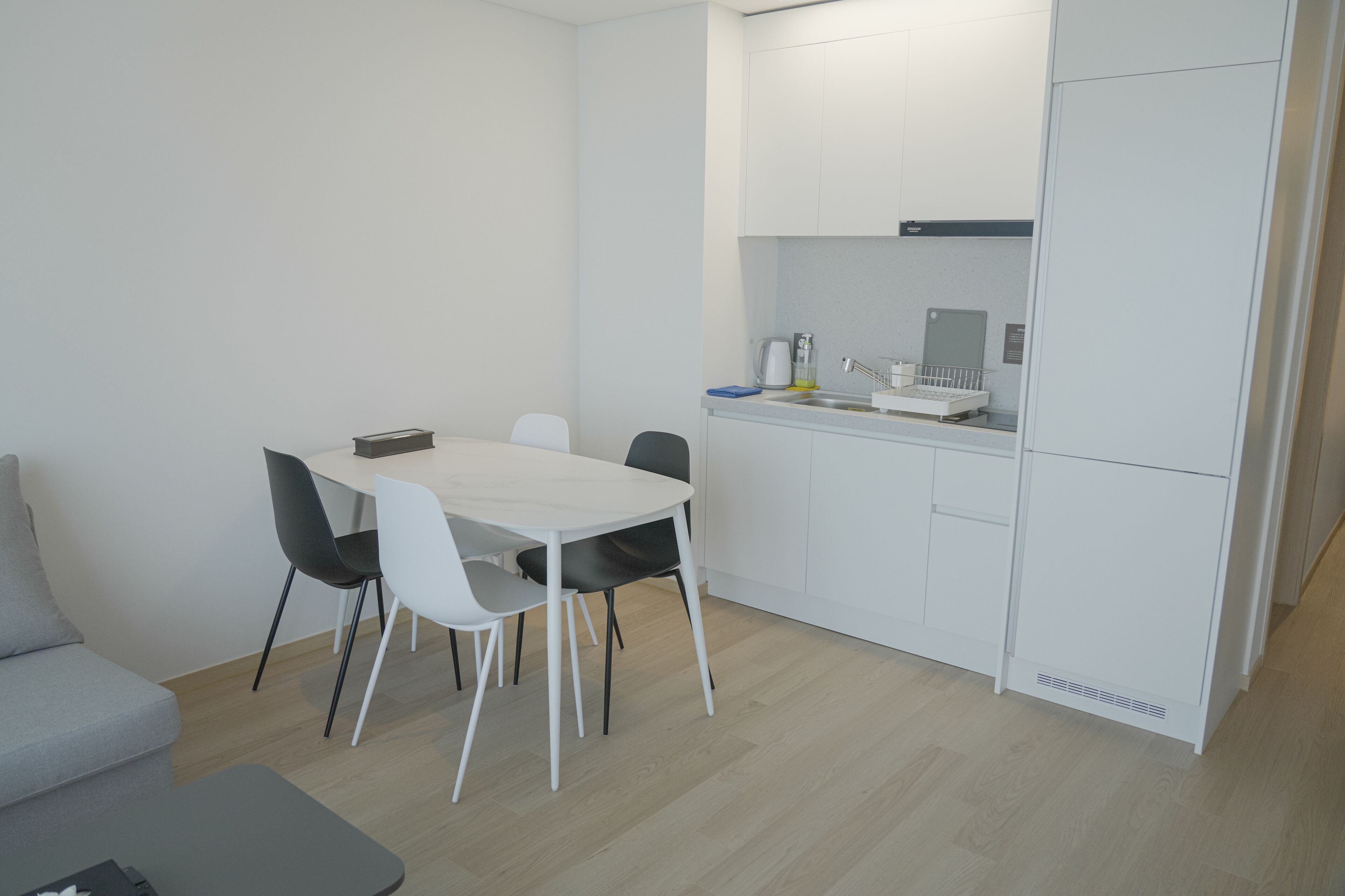Una cucina moderna con mobili bianchi, un tavolo da pranzo con sedie e un forno a incasso.