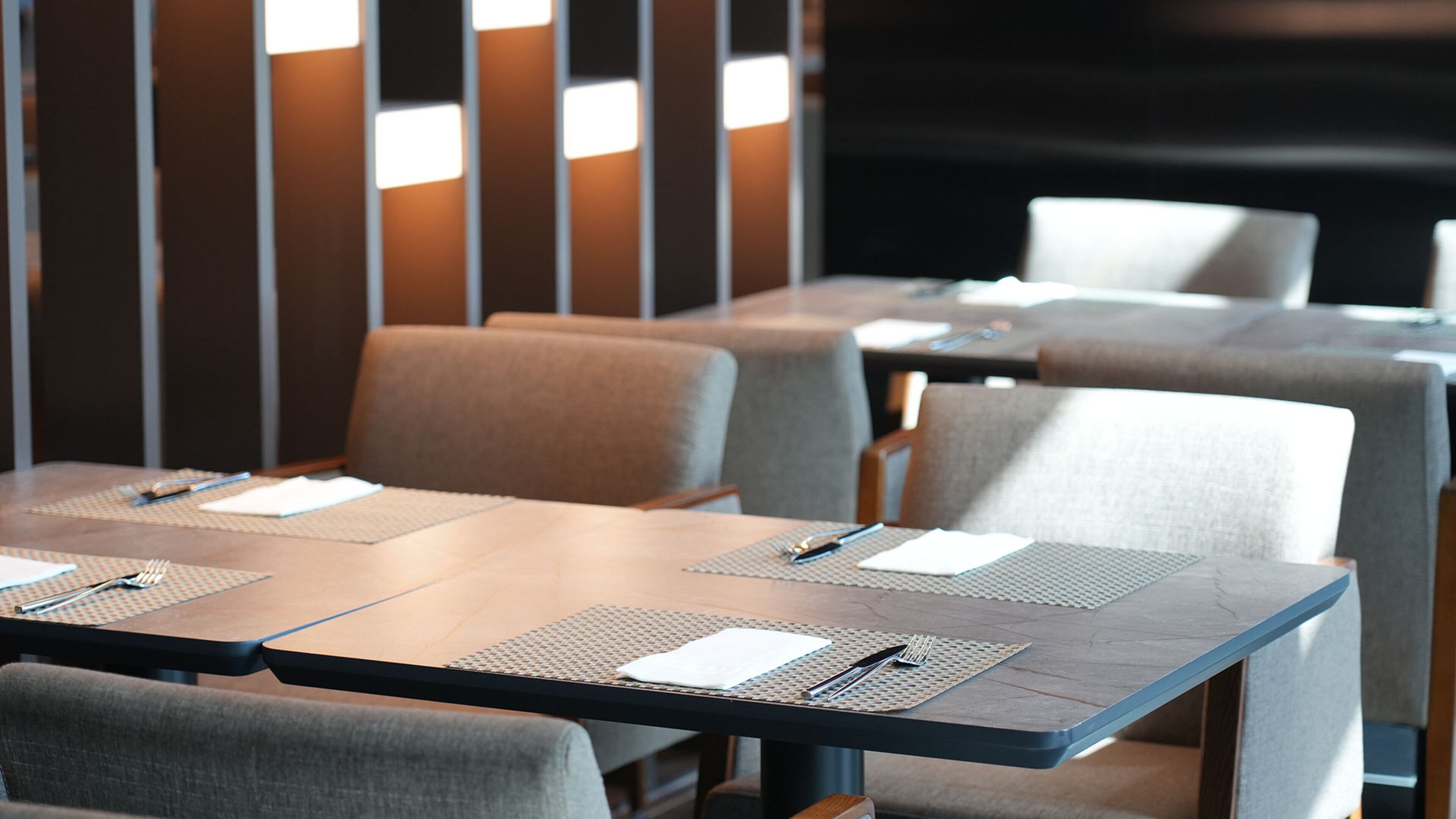 A conference room with tables and chairs, equipped with placemats and cutlery.
