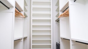 Un petit dressing étroit, doté de plusieurs étagères et d’un espace pour suspendre les vêtements.