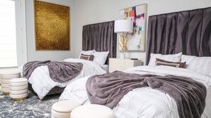 Une chambre moderne avec deux lits, une grande peinture abstraite, une lampe décorative et un sol en marbre.
