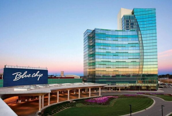 A modern hotel with a curved glass facade, a prominent Blue Chip sign, and a landscaped entrance area.