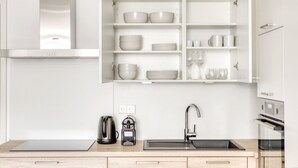 Una cocina moderna con armarios blancos, horno integrado y un lavamanos.