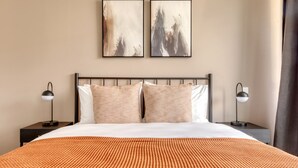 A hotel room with a large bed, two side tables, and two wall-mounted lamps.