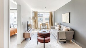 Una habitación de hotel moderna con sofá, escritorio, silla y cama.