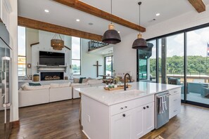 Una cocina moderna con una isla grande, muebles blancos y vistas al exterior.