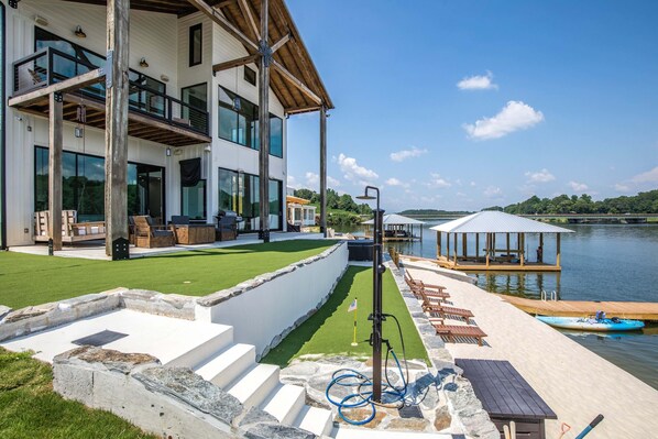 A modern house with a deck, a pool, and a gazebo by the water.