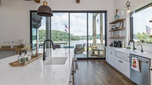 A modern kitchen with a large island, a view of a lake, and outdoor seating.