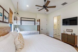 Ein Schlafzimmer mit einem großen Bett, einem Deckenventilator, einem Fernseher und einem Kleiderschrank.