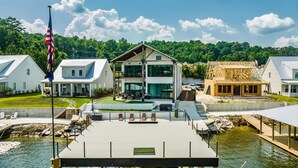 A waterfront property with a dock, a flagpole, and a two-story house with a balcony.