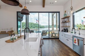 Una cocina moderna con una isla grande, vista a un lago y asientos exteriores.