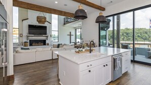 A modern kitchen with a large island, white cabinetry, and a view of the outdoors.