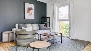 A modern living room with a grey sofa, a round table, and a bookshelf. - Amazing Landstraße 2BR w/ Elevator & Playglound, Calm Area, by Blueground (Vienna)