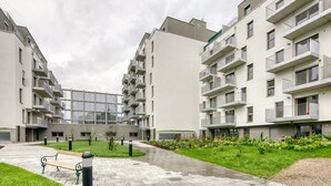 A modern apartment complex with multiple balconies, a central courtyard with a bench, and a well-maintained garden. - Amazing Landstraße 2BR w/ Elevator & Playglound, Calm Area, by Blueground (Vienna)