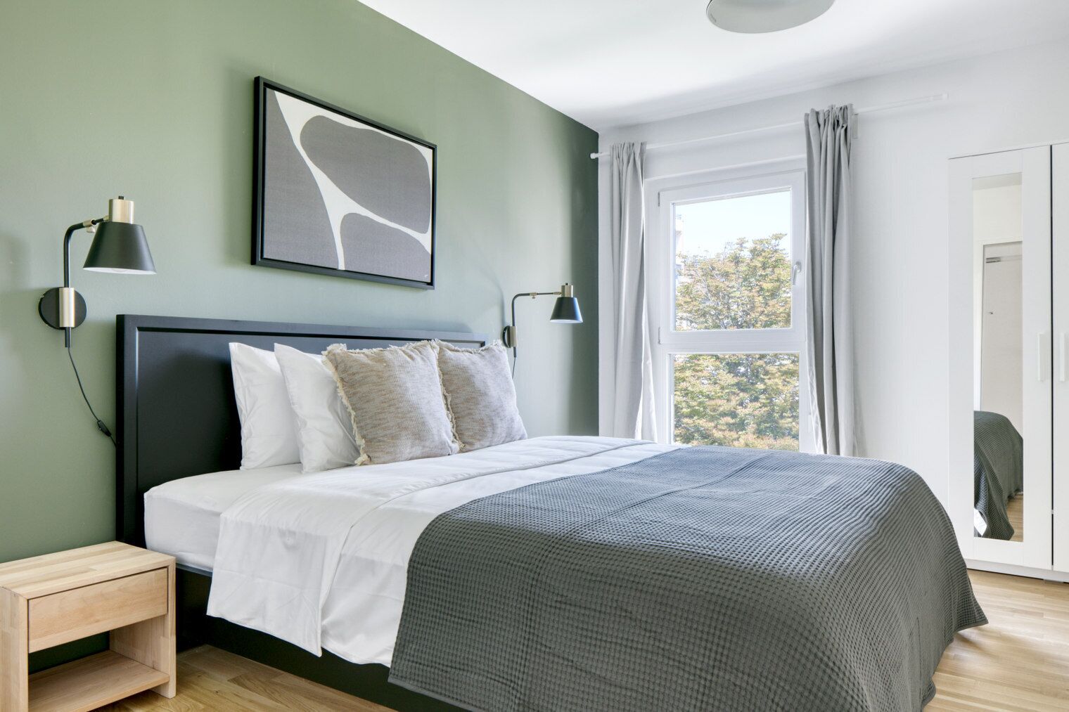 Ein modernes Schlafzimmer mit einem Bett, Nachttischen, einem Fenster mit Vorhängen und einem an der Wand hängenden, abstrakten Kunstwerk.