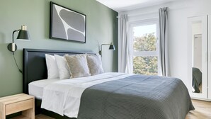 A modern bedroom with a bed, bedside tables, a window with curtains, and a wall-mounted abstract art piece. - Amazing Landstraße 2BR w/ Elevator & Playglound, Calm Area, by Blueground (Vienna)