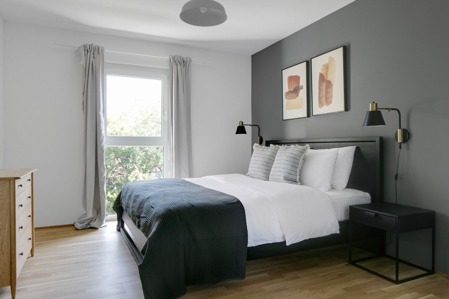 Ein modernes Schlafzimmer mit einem großen Bett, einem Nachttisch, einer Kommode und einem Fenster mit Vorhängen.