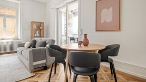 A modern living room with a grey sofa, black chairs, a round wooden table, and a large window. - Weinegg 4.5 Room w/ Storage & W/D, 2 mins to Mkt (Zurich)